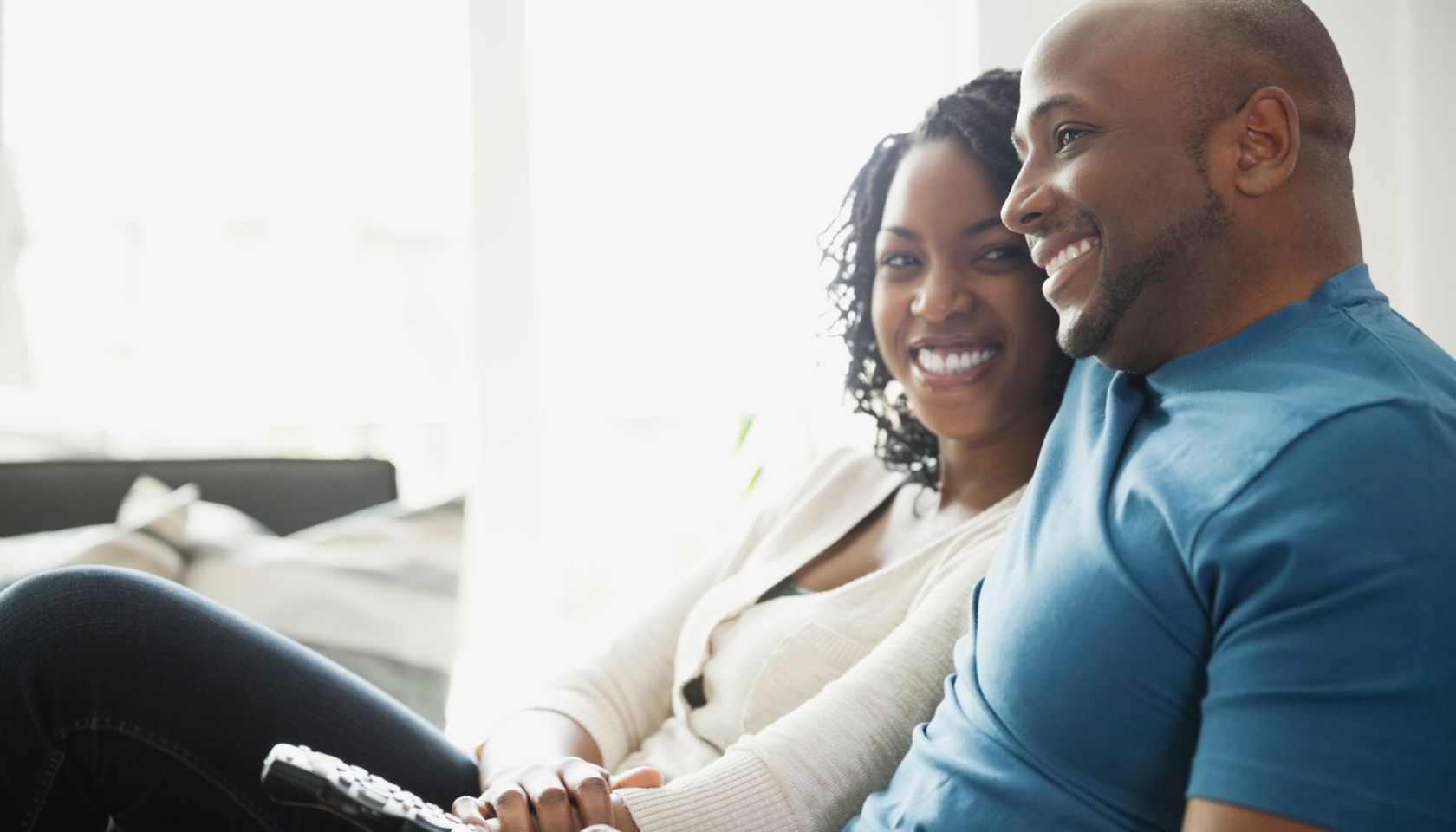 Happy couple sitting with remote control at home