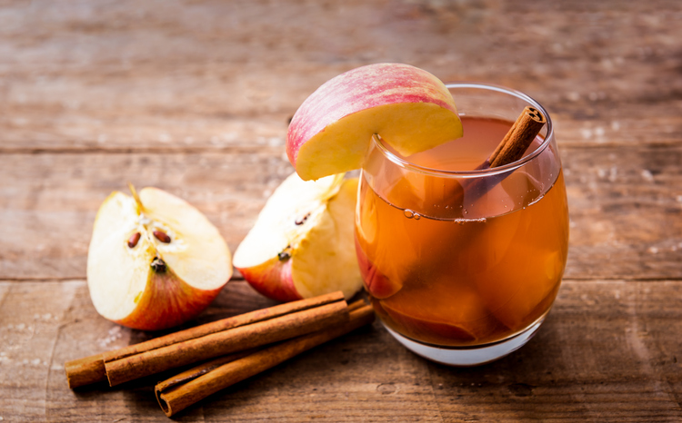 Hot apple cider with cinnamon stick on wooden background, healthy lifestyle