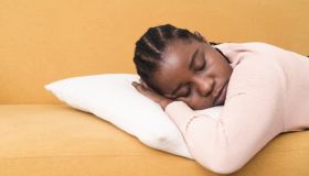 Portrait of a young Afro woman napping on the sofa due to sore throat
