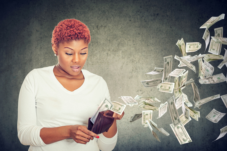 Sad woman looking at her wallet with money dollar banknotes flying away