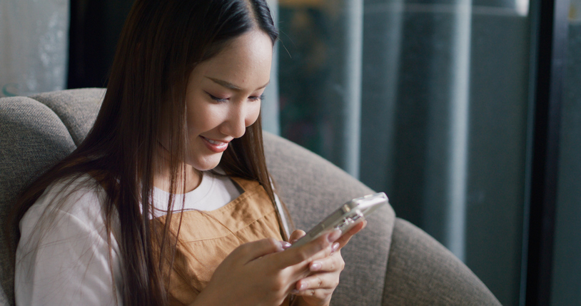 Cheerful woman playing with mobile phone.