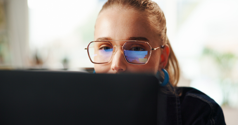 Woman, glasses and reading on laptop at house for research, editing article and feedback. Female journalist, PC and reflection for story information, proofreading headline and schedule of publication