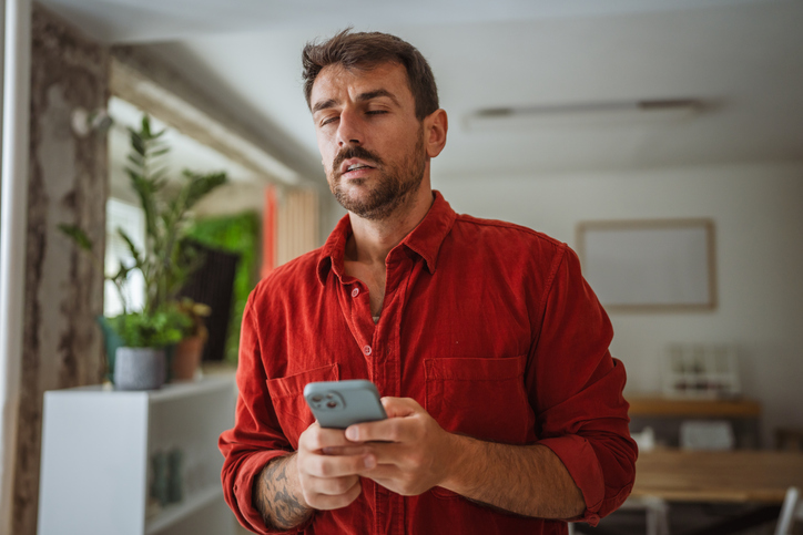 Man reading bad news on smart phone at home