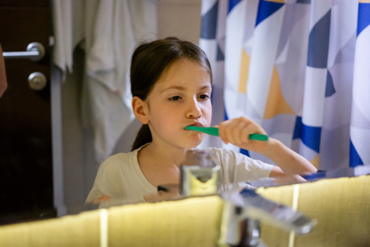 Girl brushes her teeth while looking in the mirror