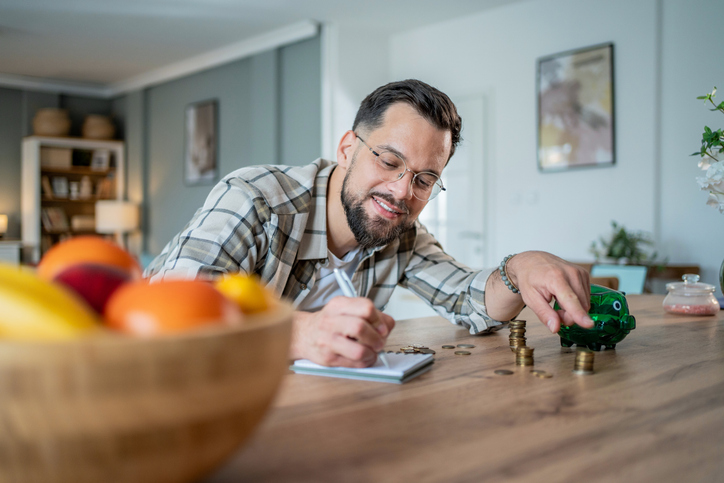 Young man budgeting and saving money at home