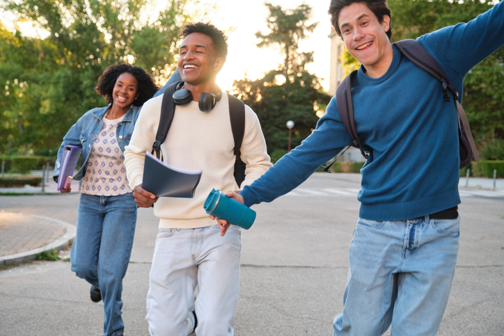 Diverse university students laughing and running on campus