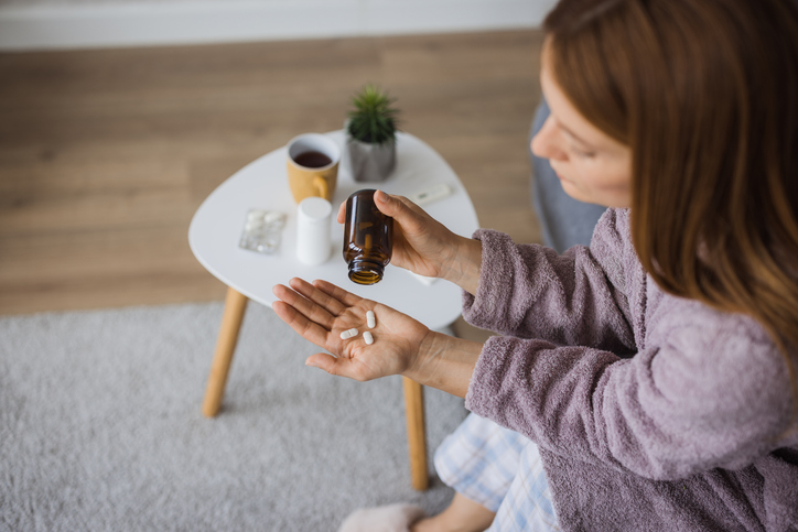 Sick woman taking pills at home