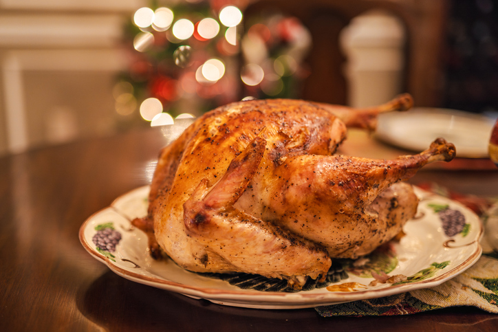 Golden roasted holiday turkey on a festive table with warm Christmas lights in the background, traditional for Christmas and Thanksgiving in the USA.