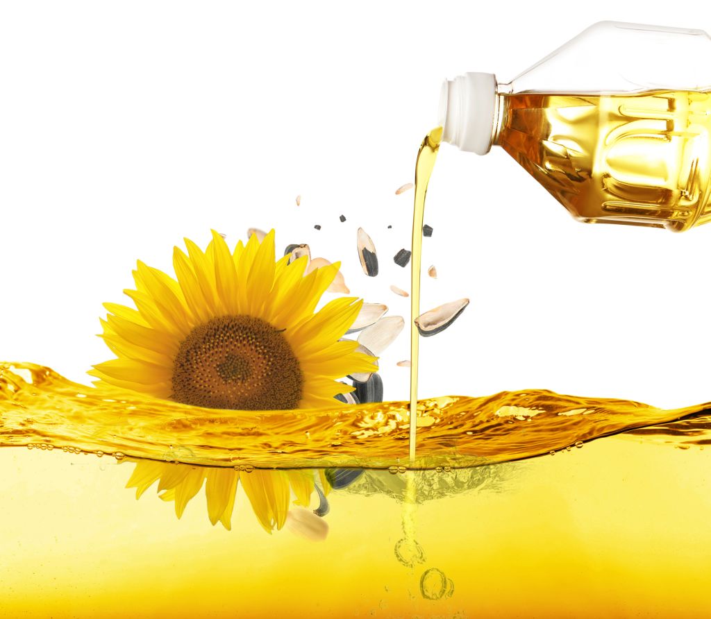 Pouring sunflower oil and falling seeds on white background