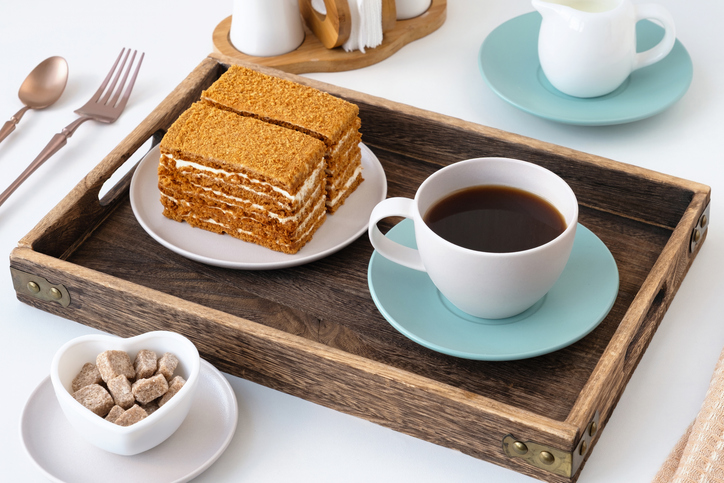 Coffee and layered dessert served on a wooden tray in a cozy setting during mid-morning