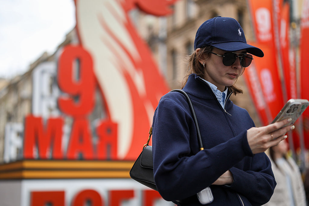 A young woman in a cap and sunglasses looks at her