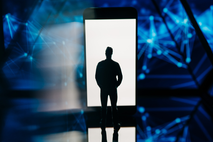 A miniature human silhouette faces a glowing smartphone screen set against a backdrop of complex blue network lines.