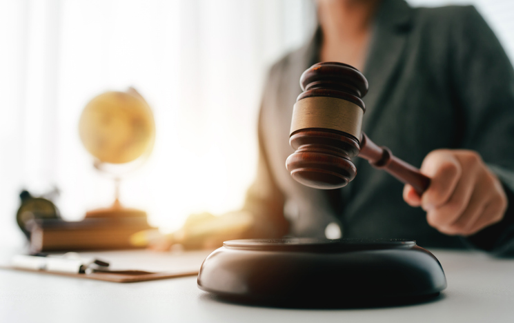 Lawyer striking gavels on sound block in law firm office, symbolizing justice, judgment, authority, legal system, court proceedings, and important legislation in legal profession