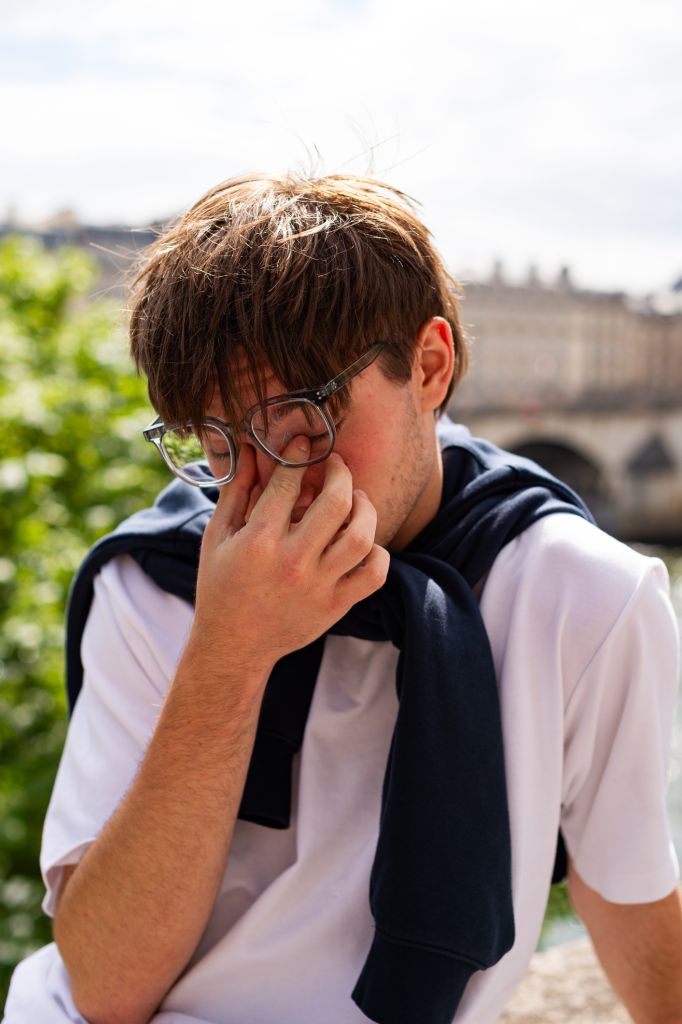 Tired Young Man Rubbing His Eyes Outdoors